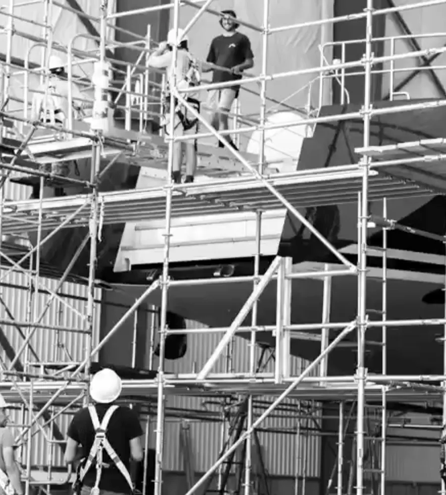 Crew installing shrink wrap containment on a tall scaffold